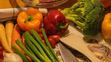 Das Bild zeigt buntes Obst und Gemüse und einige Küchengeräte